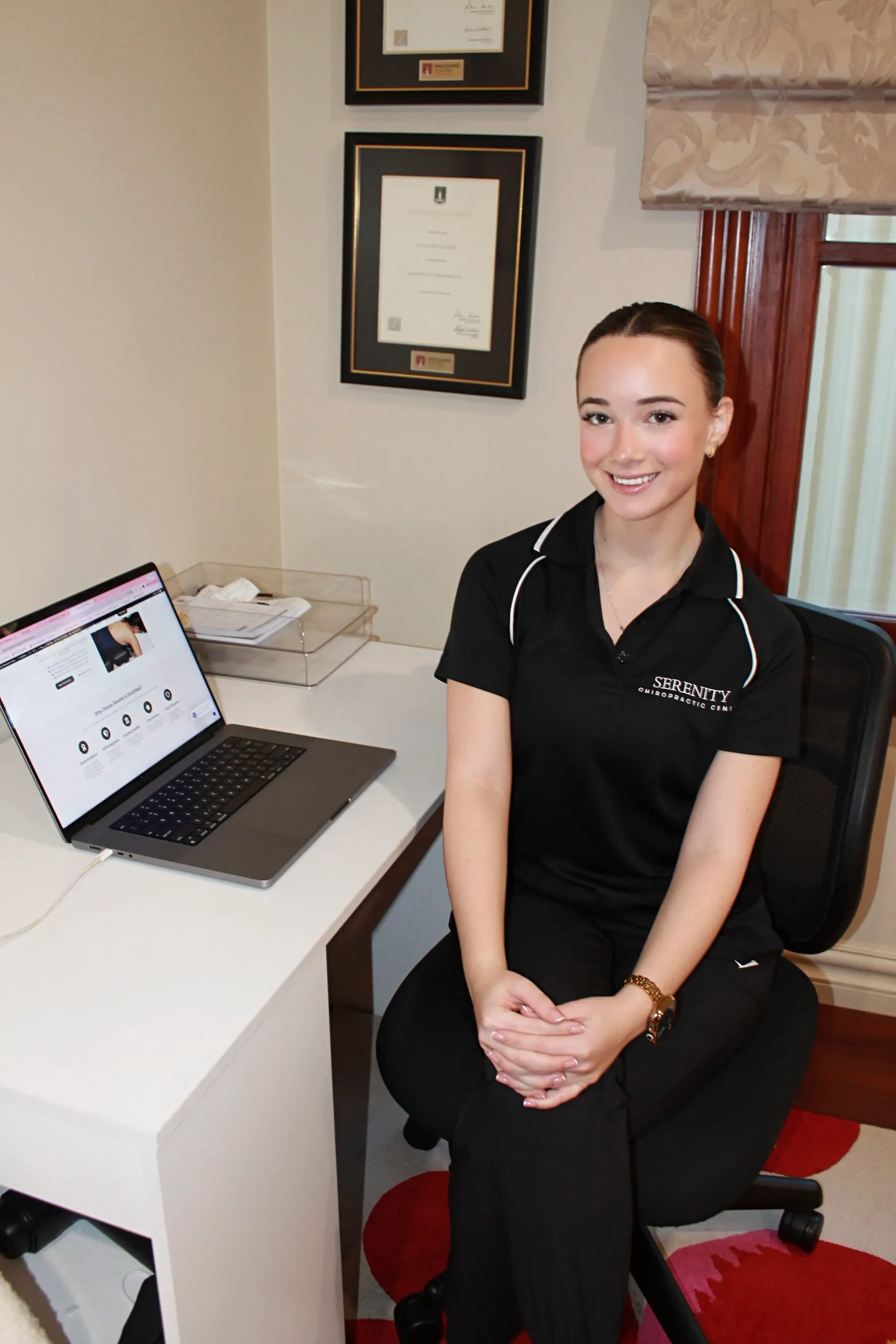 Alicia Neil smiling at her desk in the Strathfield clinic, her Macquarie University degrees on the wall