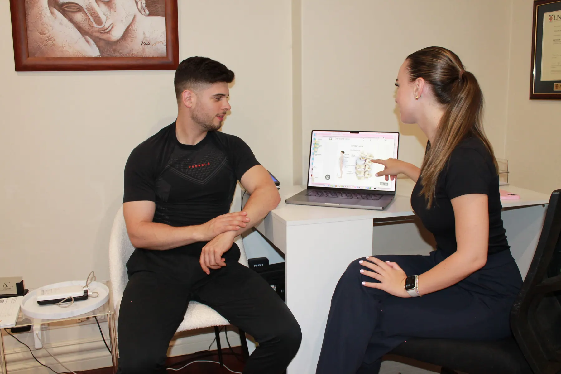 Alicia Neil explaining spinal anatomy to a patient on a laptop