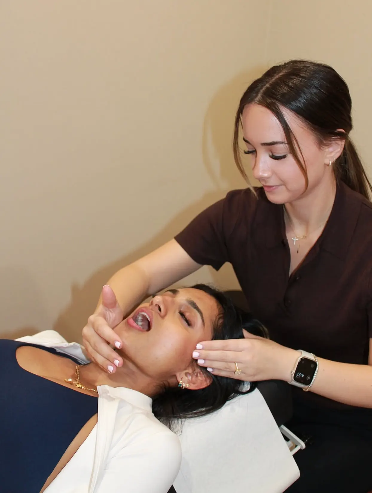 Alicia Neil gently treating a patient's jaw and upper neck