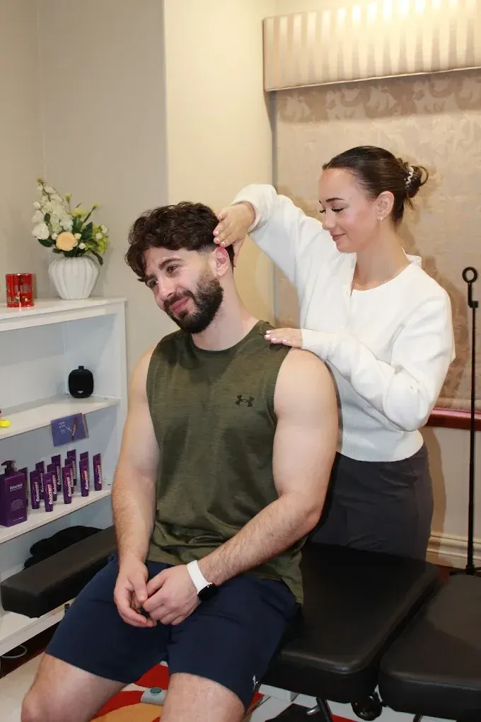 Alicia Neil massaging a seated patient's neck and shoulder